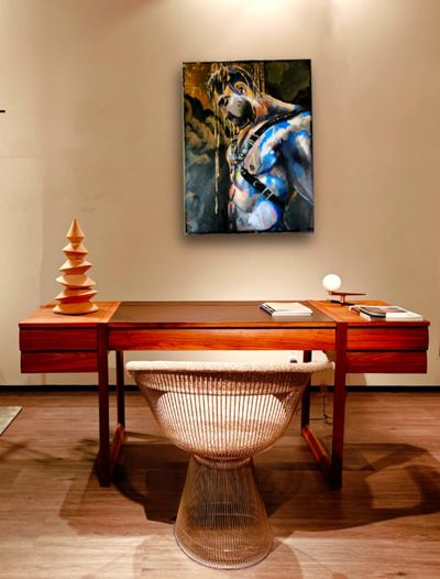Expressief figuratief schilderij van een klassieke mannelijke figuur in blauw, wit en goud boven een modern houten bureau in een stijlvol interieur.
